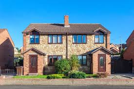 A stone-fronted semi-detached house with a front garden