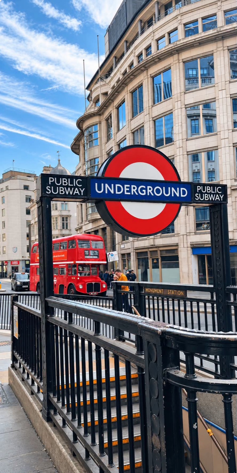 An Underground sign at Monument station with a red Routemaster bus behind